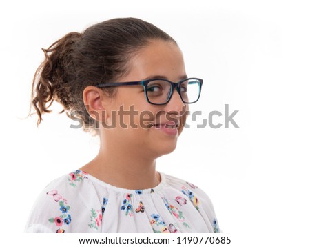 portrait of a young girl wearing glasses and a flower printed blouse doing funny faces isolated on white background