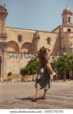 girl posing against the backdrop of the sights, on the model a green sundress and a wicker bag, enjoying the view and traveling around Еurotour