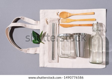 Fabric bags, glass jars, metal straws, bamboo cutlery on grey background with copy space. Eco friendly and reuse concept. Top view. Flat lay. Zero waste concept