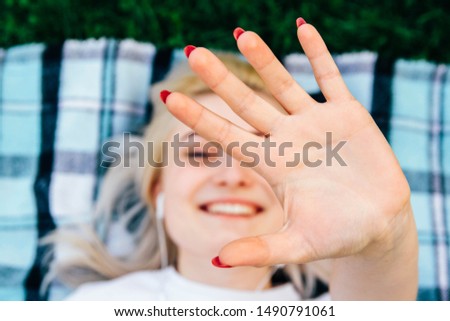 Beautiful blonde girl smiling making frame with hands and fingers with happy face lying on rug green background. Lifestyle concept. Top view. Copy, empty space for text. Creativity and photography