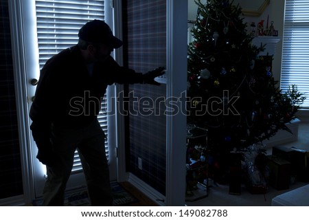 This photo illustrates a burglary or thief breaking into a home at night through a back door during the Christmas Holiday Season. View from inside the residence.