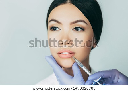 asian woman plumper lips, getting bigger lips. prick of a syringe for the lips. injections for bigger volume Royalty-Free Stock Photo #1490828783