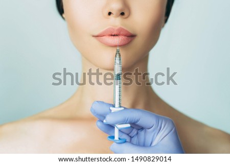 woman's plumper lips, getting bigger lips. prick of a syringe for the lips. injections for bigger volume Royalty-Free Stock Photo #1490829014