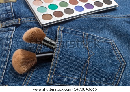 Large makeup brushes in pocket of blue jeans. Concept, commercial work of a makeup artist, for printing business cards and brochures.