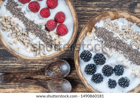 Smoothie in coconut bowl with blackberries, raspberries, oatmeal, sunflower seeds and chia seeds for breakfast , close up. The concept of healthy eating, superfood. Top view