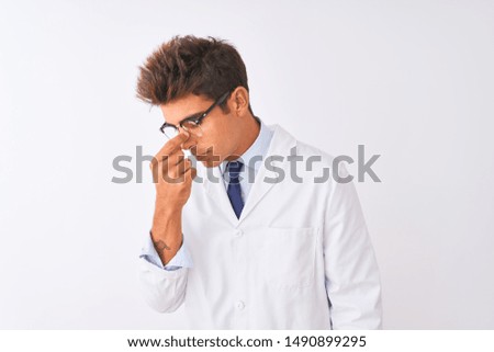 Young handsome sciencist man wearing glasses and coat over isolated white background tired rubbing nose and eyes feeling fatigue and headache. Stress and frustration concept.