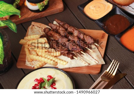 kabab meal with homas and konafa on wood table