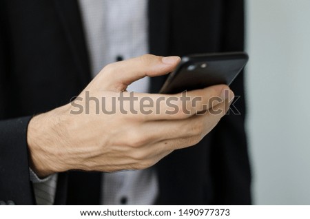 Businessman in suit take phone in hand and message.