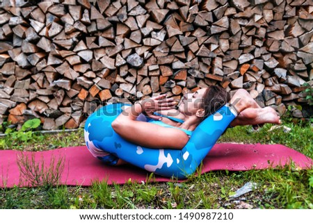 girl practicing yoga nidrasana in the forest against wood background