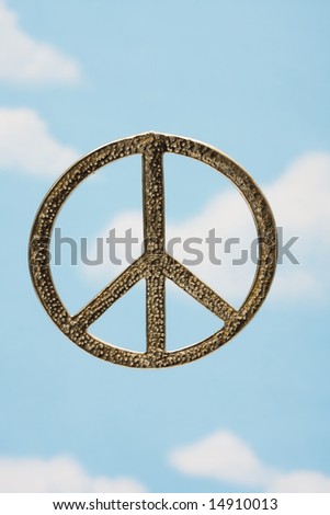 A silver peace symbol with a sky background