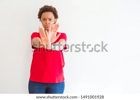 Young beautiful african american woman over white background Rejection expression crossing arms and palms doing negative sign, angry face
