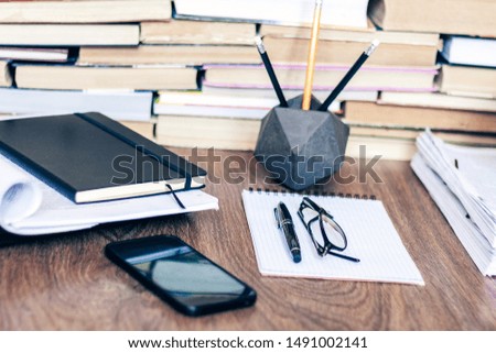 Stack of old book on wooden table, laptop computer, notebook, smartphone, stationery and paperweight. Education writer concept background