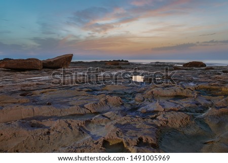 Half an hour before sunrise on the rocky coast of La Mata near the Spanish city of Torrevieja. Large stones lie in the foreground in front of a beautiful dawn over the Mediterranean sea.