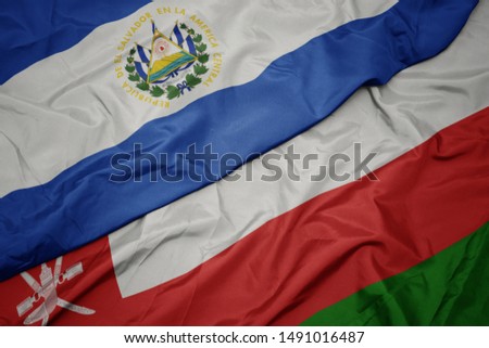 waving colorful flag of oman and national flag of el salvador. macro