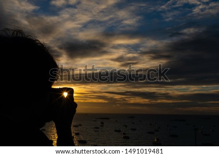 the silhouette of man using camera to taking the photo of sunset and sun ray
