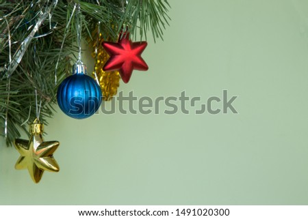 Christmas decoration. Natural pine branches on a green background ith blue ball and yellow Xmas red stars and New Year's toys. Copy space.