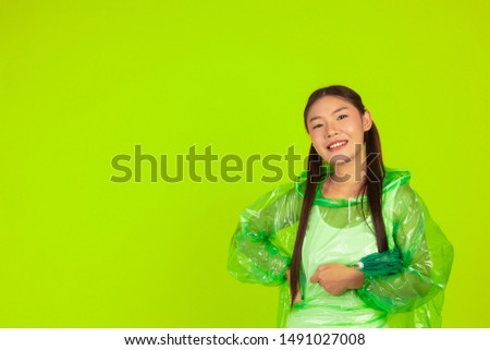 Girl is wearing a green rain dress on a green background.