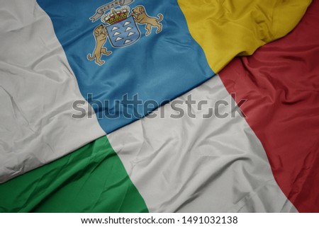 waving colorful flag of italy and national flag of canary islands. macro