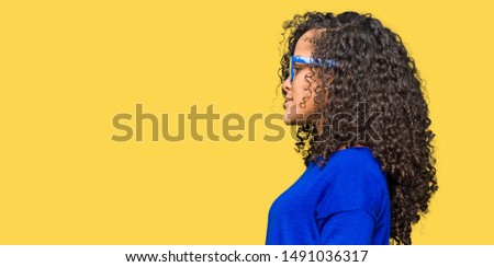 Young beautiful woman with curly hair wearing glasses looking to side, relax profile pose with natural face with confident smile.