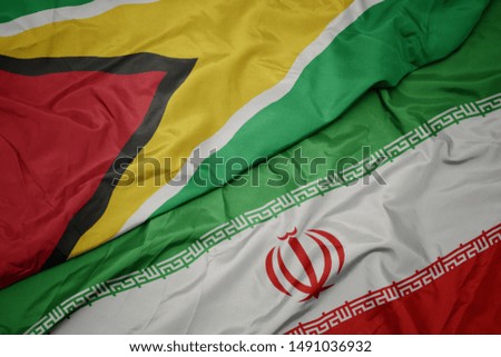 waving colorful flag of iran and national flag of guyana. macro