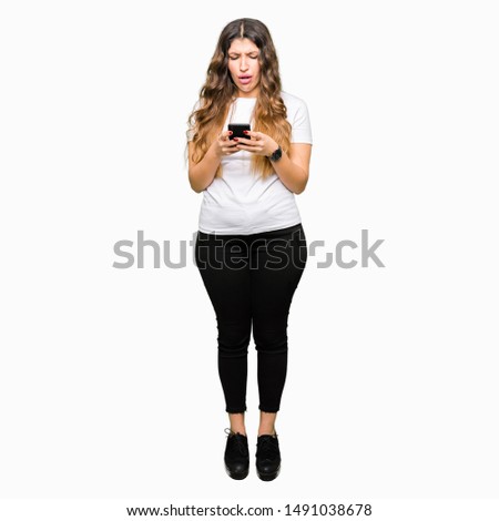 Young adult woman using smartphone scared in shock with a surprise face, afraid and excited with fear expression