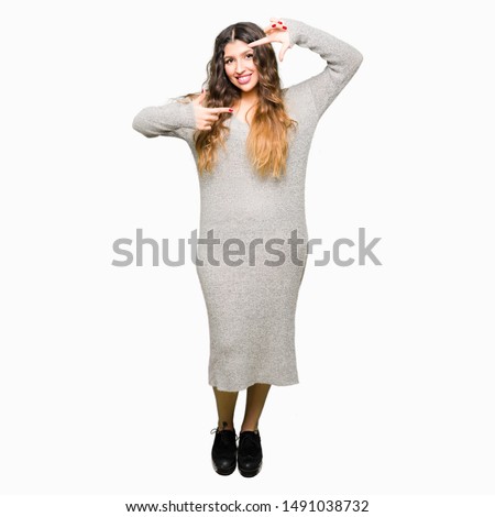 Young beautiful woman wearing winter dress smiling making frame with hands and fingers with happy face. Creativity and photography concept.