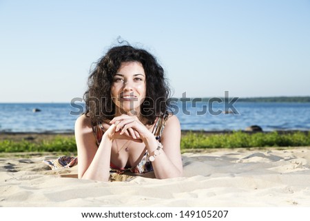 Happy woman with dark hairs lying at beach