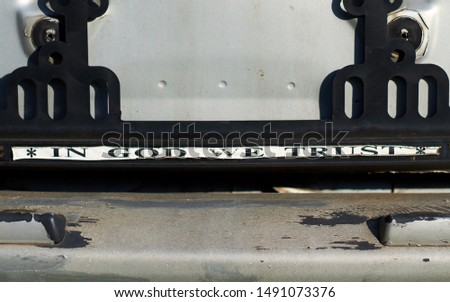 Lettering on car number plate holder *in got we trust*