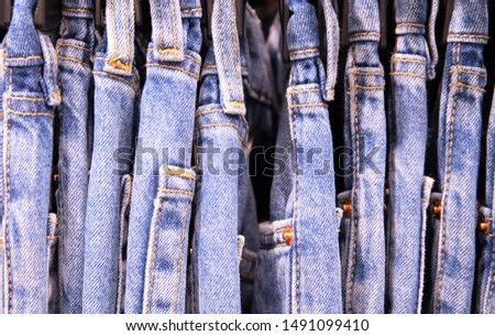 Several pairs of blue jeans on hanger, close up photo. Jeans size row. Tie Dye jeans clothes photo. Everyday wear on hanger in store. Fashion shop Black Friday sale. Trendy clothes department store