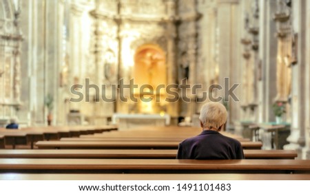 A blurry atmospheric image of an unknown woman with white hair sitting alone in an unidentified church  Royalty-Free Stock Photo #1491101483