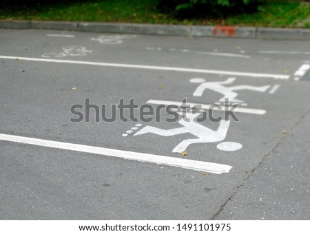 White markings on the road in the form of people on roller skates