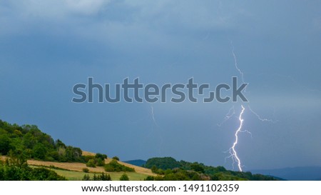 Storm with lightning over the hilly landscape