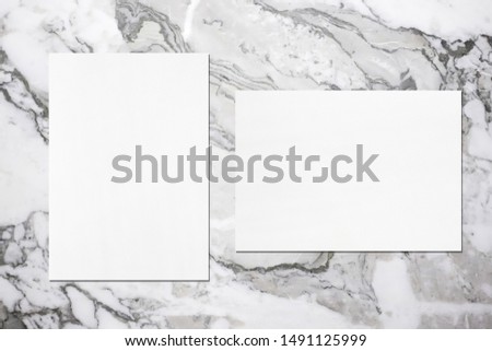 Two empty white vertical and horizontal rectangle poster mockups with soft shadows on grey marble background. Flat lay, top view