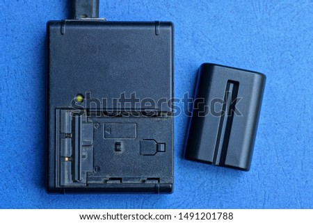  black charger and battery lies on a blue table