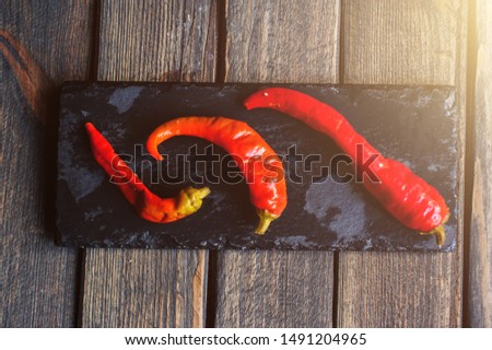 red pepper on a black plate over dark wooden background