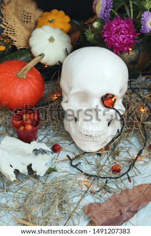 Halloween decorative composition of skulls, pumpkins, leaves, illuminations, mystical decor on a wooden surface, autumn seasonal holidays
