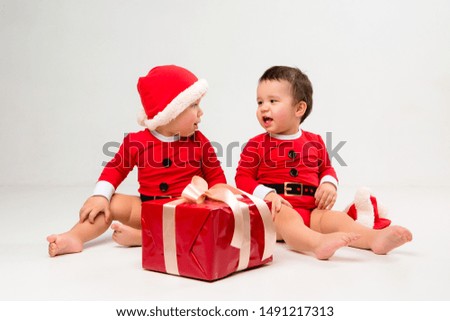 
two toddlers in Santa Claus costumes with gift box on white isolate background
