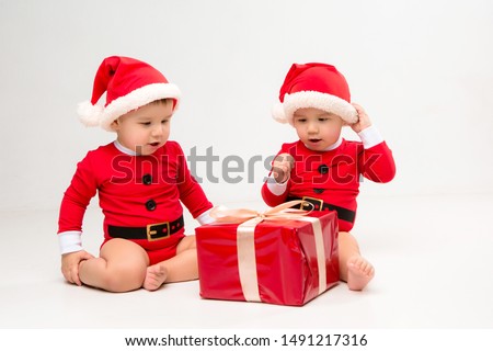
two toddlers in Santa Claus costumes with gift box on white isolate background