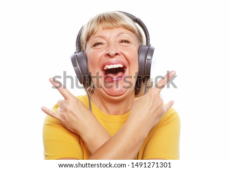 People, emotion and technology concept: portrait of senior woman listening to music with headphones isolated on white background