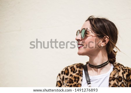 Outdoor close up fashion portrait of elegant woman looking aside and wearing trendy animal, leopard print faux fur coat, stylish sunglasses posing on white background.Copy, empty space for text