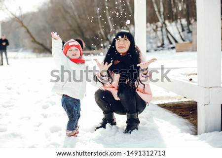 Family in a winter park. Elegant woman in a pink jacket. Mother with little daughter