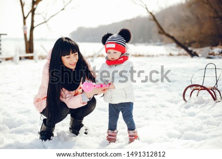 Family in a winter park. Elegant woman in a pink jacket. Mother with little daughter