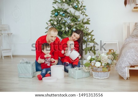 Cute family have fun in decorating room. Beautiful mother with little children and husband. Family in a red sweaters