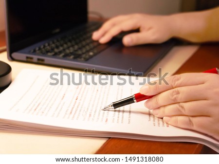 blur proofreading paper and computer laptop on table under lamp light Royalty-Free Stock Photo #1491318080