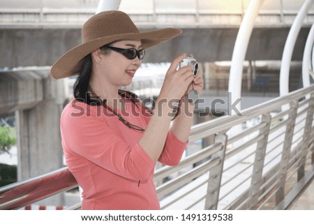 Asian woman tourist standing and holding camera for taking photo at skytrain station.