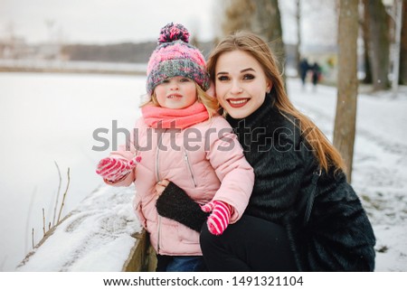 Elegant mothe with little daughter. Woman walking with her daughter. Family in a winter park