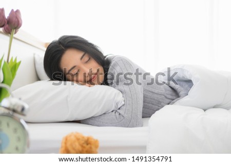 Young beautiful Asian woman has a sweet dream and lies on one's side on bed in the bedroom. Royalty-Free Stock Photo #1491354791