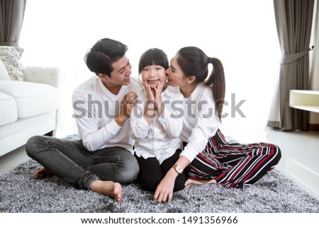 Asian family Father and mother kiss the child cheek in the house.