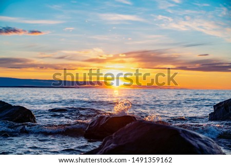 Waves splashing over the rocks in the summery sun set in Hållnäs, Sweden