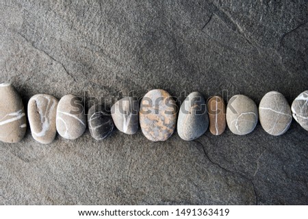Smooth Stones in a row placed on gray rock slab. Still Life Photography.